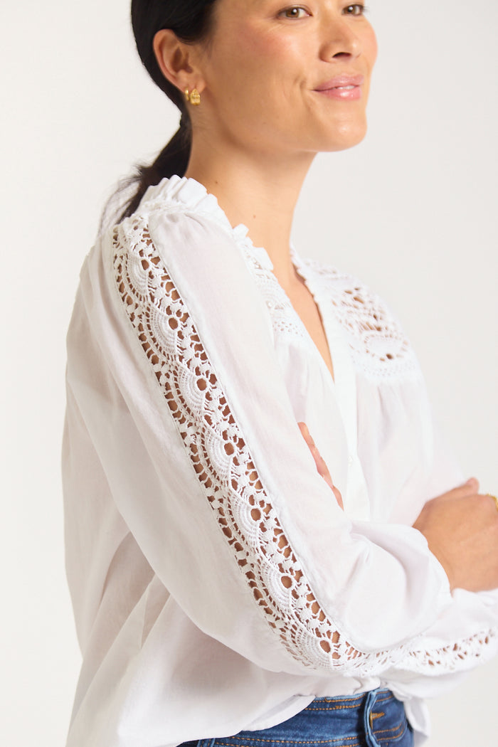 Woman turned to the side showcasing lace details down sleeve of shirt.