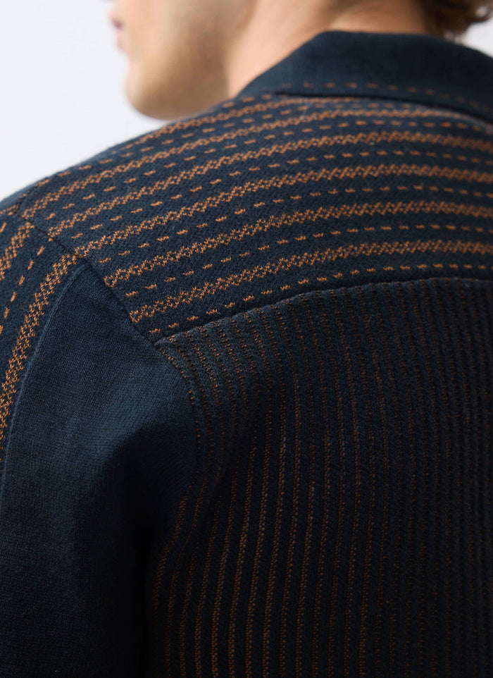 A close-up view of the intricate brown jacquard knit pattern on the shoulder of the black Percival Appendix Knitted Shirt.