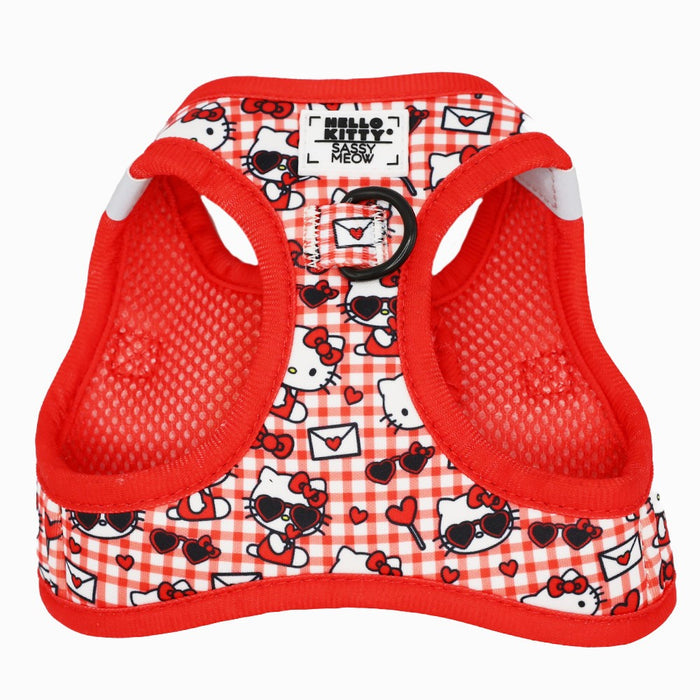 The Cat Step-In Harness - Hello Kitty® Red Classic by Sassy Woof features red and white plaid neoprene mesh with Hello Kitty faces, hearts, bows, a black metal D-ring, and a Sassy Woof label. Part of the Sanrio collection.