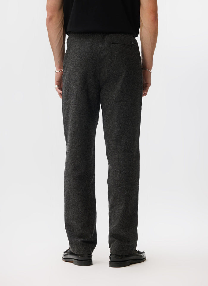 The back view of a model wearing the Percival Caxton Smart Trousers in black brushed wool against a white studio background.
