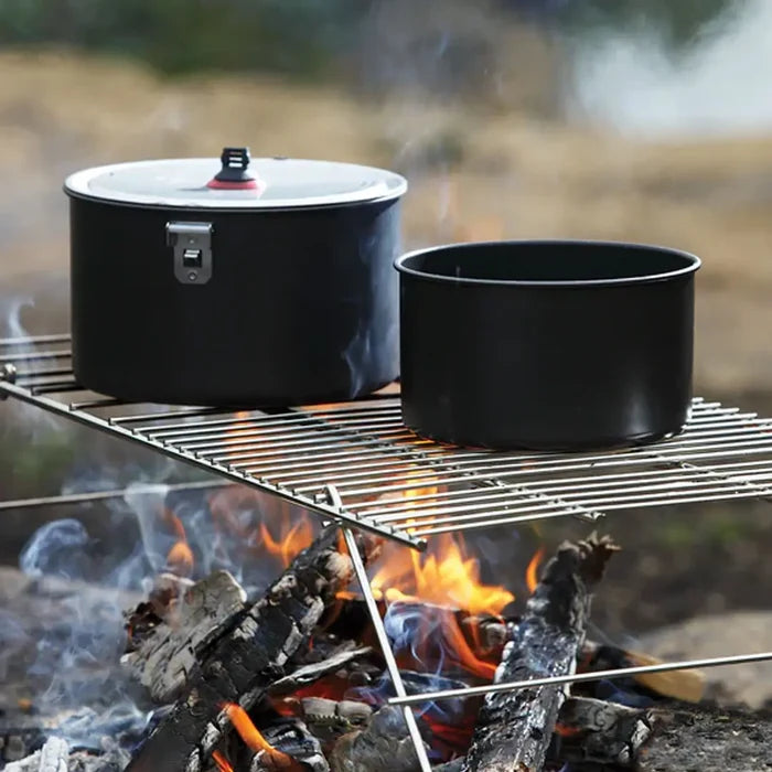 Coghlans collapsible camp fire grill used on top of a fire holding two large cooking pots
