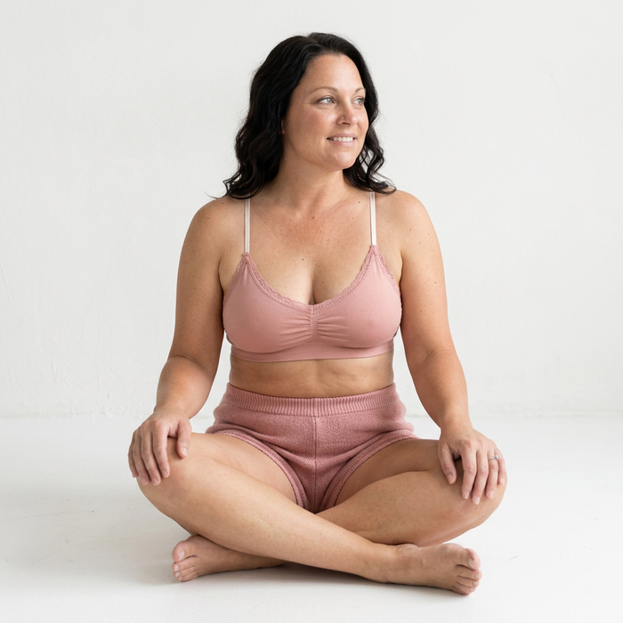 Woman wearing a pink bikini sitting on a white background