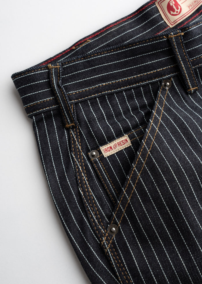 Close-up of Iron & Resin pinstripe denim pants with visible stitching and label, showcasing quality craftsmanship.