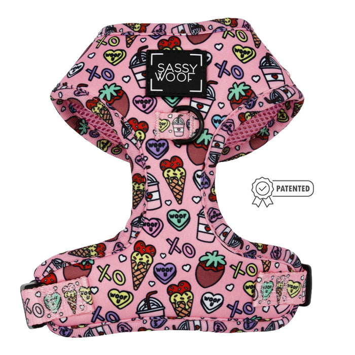 The Sassy Woof Dog Adjustable Harness - I Chews You features a pink base with colorful hearts, strawberries, paw prints, ice cream cones, and “woof” & “XOXO” accents—ideal for your pup’s growth.