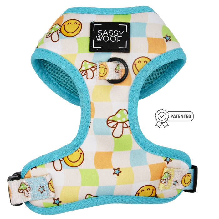 The Sassy Woof Dog Adjustable Harness - Mush Love features a checkered pattern with smiley faces, mushrooms, blue trim, and an adjustable no pull design. A Patented badge appears to the right of the branded front.