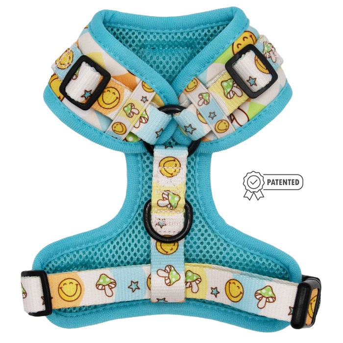 The Sassy Woof Dog Adjustable Harness - Mush Love is a turquoise no pull harness with white straps, featuring yellow smiley faces, mushrooms, and stars, plus a PATENTED badge on the right side.