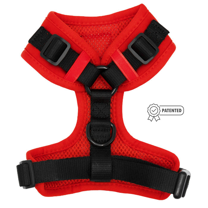 The Sassy Woof Dog Adjustable Harness in Neon Red features a mesh design, sturdy buckles, center D-ring, and a patented badge on the right. This no pull harness is shown laid flat with red and black accents.