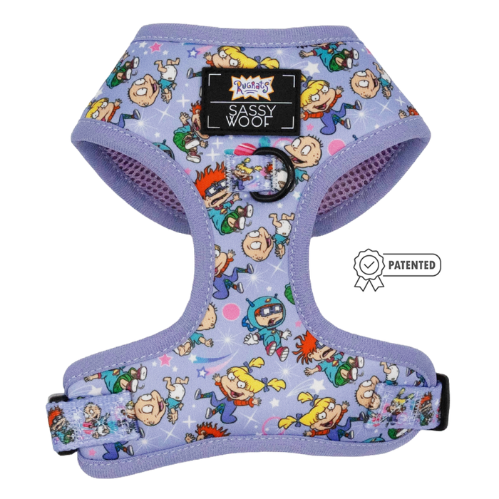 The Dog Adjustable Harness - Nickelodeon Rugrats™ by Sassy Woof features a lavender design with colorful Rugrats characters, a front Sassy Woof label, black metal leash ring, and is shown beside the Puppy Growth Pawtection Plan badge.