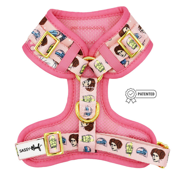 The Sassy Woof Dog Adjustable Harness - STAR WARS™ Princess Leia is pink with gold hardware, features cartoon faces of Princess Leia in different hairstyles, and displays the Sassy Woof label and a PATENTED icon.