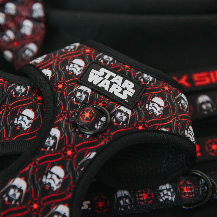 A close-up of the Sassy Woof Dog Adjustable Harness - STAR WARS™ The Dark Side, featuring a black, red, and white design with Stormtrooper and Darth Vader helmets, a Star Wars logo patch, O-ring for leash, and adjustable fit for comfort.