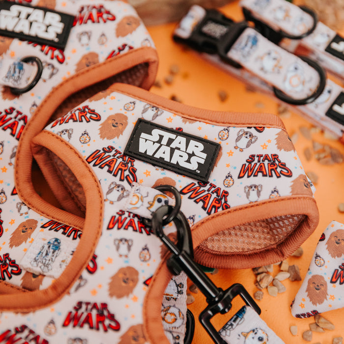 A close-up of the Sassy Woof STAR WARS™ The Rebel Alliance Dog Adjustable Harness, featuring cartoon Chewbacca, R2-D2, and Ewok designs with orange trim and Star Wars text on a white background.