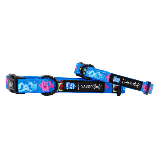 Two adjustable Sassy Woof Dog Collars - Blue's Clues™ feature playful Magenta prints, black buckles, metal rings, and black labels with Blue’s Clues and Sassy Woof logos. Both collars are shown overlapping on a white background.