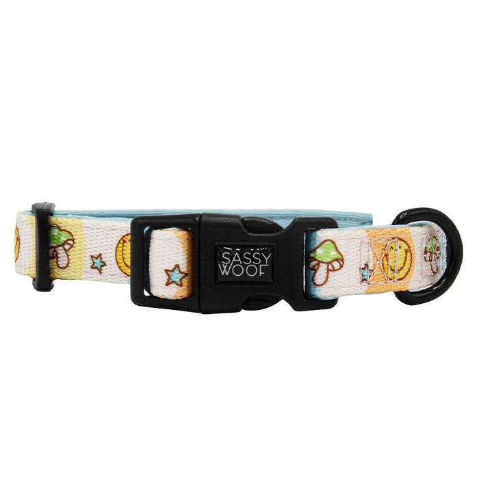 The Sassy Woof Dog Collar - Mush Love is a white, adjustable collar with a sturdy D-ring, black plastic buckle featuring the brand logo, and colorful mushroom, star, and moon illustrations.