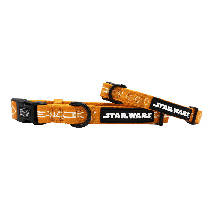 The Sassy Woof Dog Collar - STAR WARS™ Ahsoka features an orange design with black and white logos, geometric patterns, adjustable sizing, a black plastic buckle, and a metal ring for tags or leash attachment.