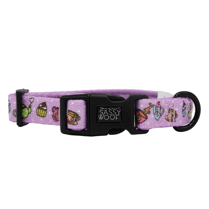 The Sassy Woof Dog Collar - Tea Pawty is a lavender neoprene collar with a sturdy D-ring, black buckle, and colorful teapots and cupcakes. It’s fully adjustable and features the Sassy Woof brand name on the buckle.
