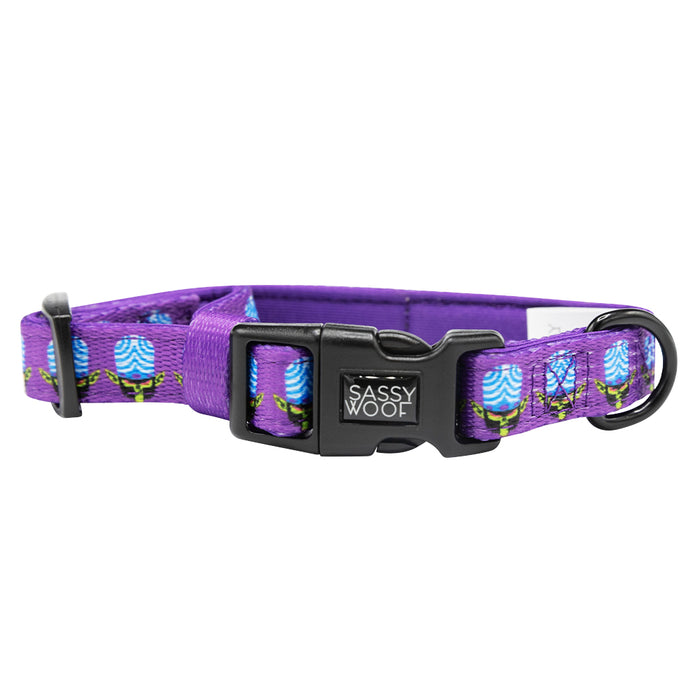 A stylish dog collar from Sassy Woof’s Dog Collar Three Piece Bundle – Mojo Jojo™, featuring a vibrant purple design with a floral pattern, durable black plastic buckle, sturdy D-ring, and a signature Sassy Woof tag—ideal for matching with your favorite Powerpuff Girls pet accessories.