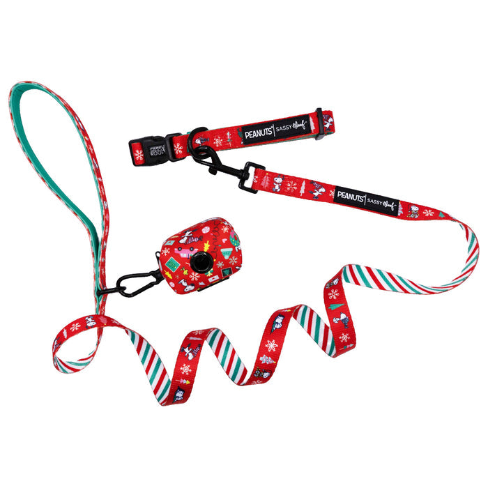 Celebrate the holidays with the Dog Collar Three Piece Bundle - Peanuts™ Beagle Bells by Sassy Woof, featuring a festive collar and leash set adorned with cheerful Snoopy and holiday patterns. The coordinating waste bag holder matches the seasonal theme, while the leash is finished with a striped green, red, and white underside for extra holiday flair.