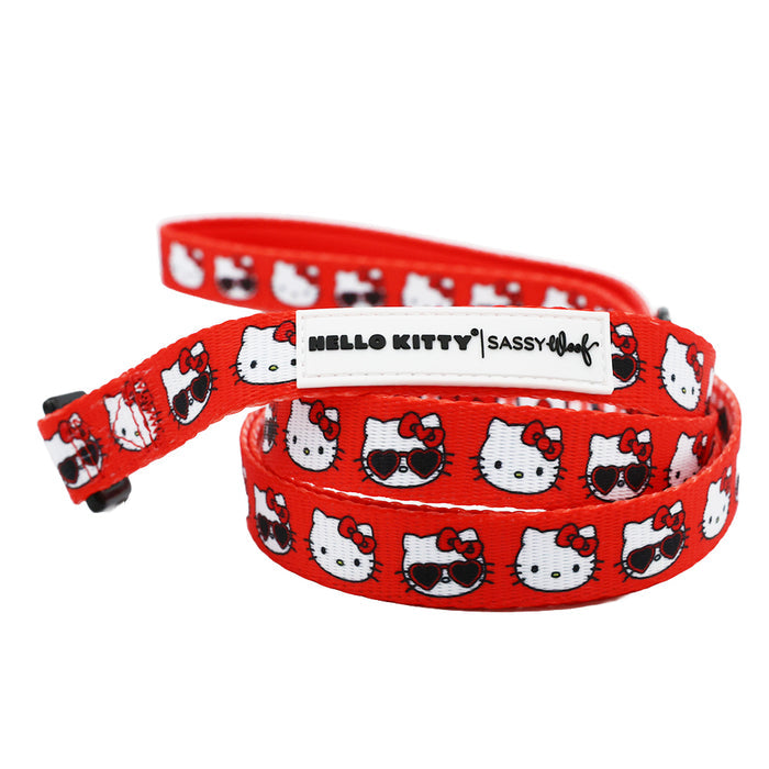 The Sassy Woof Dog Four Piece Bundle - Hello Kitty® Red Classic features a bright red collar and leash with repeating Hello Kitty faces—some in sunglasses—and a “HELLO KITTY | Sassy Woof” leash label. Complements your favorite adjustable harness.