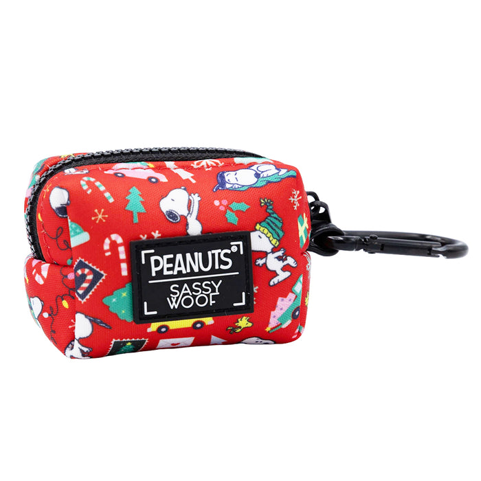 The Sassy Woof Dog Four Piece Bundle - Peanuts™ Beagle Bells includes a festive red pouch with Snoopy, Woodstock, and holiday prints. It features Peanuts and Sassy Woof labels, a zipper, and black clip for your dog's holiday accessories.