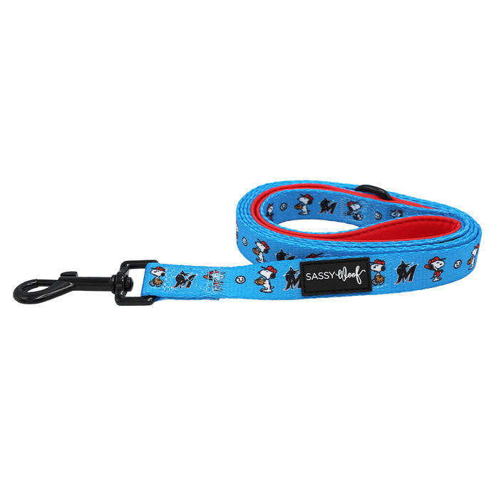 The Sassy Woof Dog Leash - MLB™ x Peanuts™ Miami Marlins™ features cartoon dog and bone prints, a black metal clasp, red inner lining, and a Sassy Woof patch—ideal to match with Peanuts Snoopy dog gear. The leash is coiled on a white background.