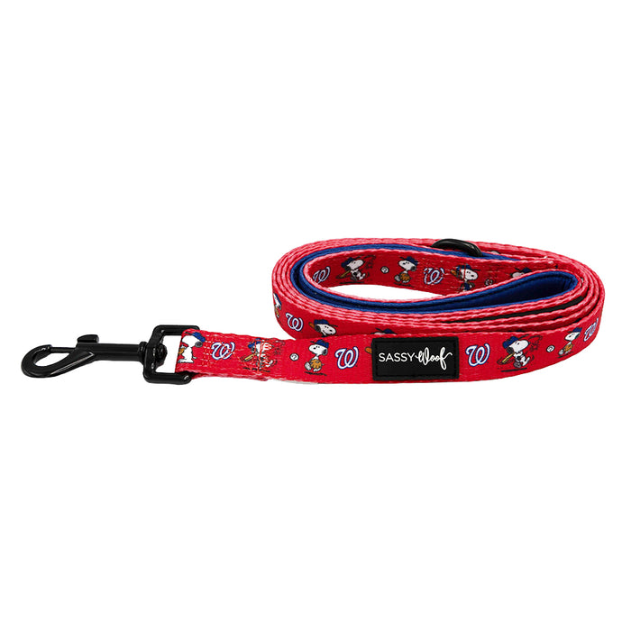 The Sassy Woof Dog Leash - MLB™ x Peanuts™ Washington Nationals™ is red, features Snoopy and Woodstock cartoon images, a blue inner lining, black metal clip, and a Sassy Woof label on the side.