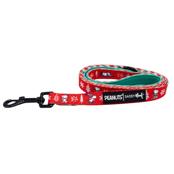 The Sassy Woof Dog Leash - Peanuts™ Beagle Bells features festive Snoopy designs, a red exterior, teal interior, black metal clip, and a PEANUTS | Sassy Woof label—perfect for holiday dog accessories.