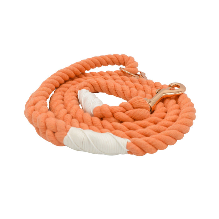The Sassy Woof Dog Rope Leash - Clementine features hand-crafted coiled orange rope with white wrapped accents near the handle and clasp, plus a gold metal clip for collar attachment, shown on a white background.
