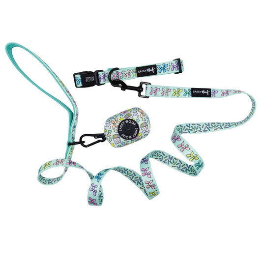 The Sassy Woof Dog Three Piece Bundle - Pup Pup Hooray includes a leash, collar, and waste bag holder with butterfly and leaf patterns on white, teal accents, and black hardware—ideal for celebrating your pup’s birthday in style.