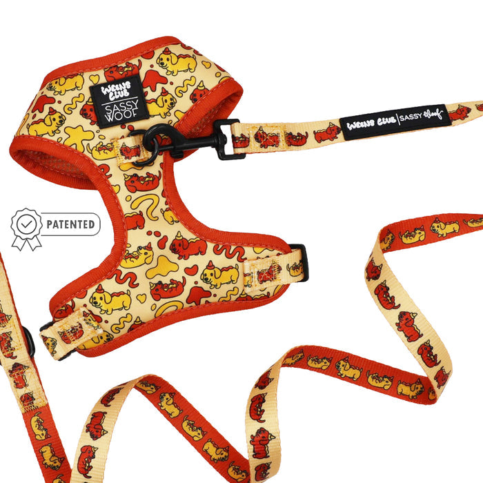 The Sassy Woof Dog Two Piece Bundle - Hot Dawg includes a yellow and orange adjustable harness and matching leash with playful dog patterns, plus a patented badge to the left of the harness.