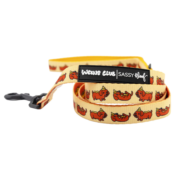 The Sassy Woof Dog Two Piece Bundle - Hot Dawg includes a yellow leash with cartoon corgi patterns, a black clasp, and a label reading "Weens Club | Sassy Woof." It pairs perfectly with our adjustable dog harness.