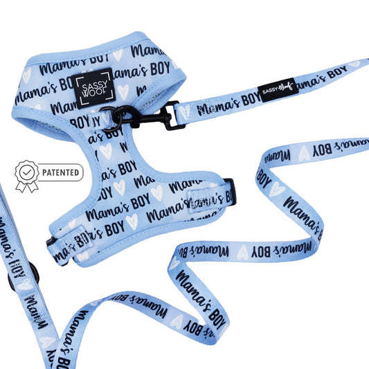 The Sassy Woof Dog Two Piece Bundle - Mama's Boy features a light blue adjustable harness and leash with "Mamas Boy" and white heart prints, plus a patented badge icon for stylish puppy growth protection.