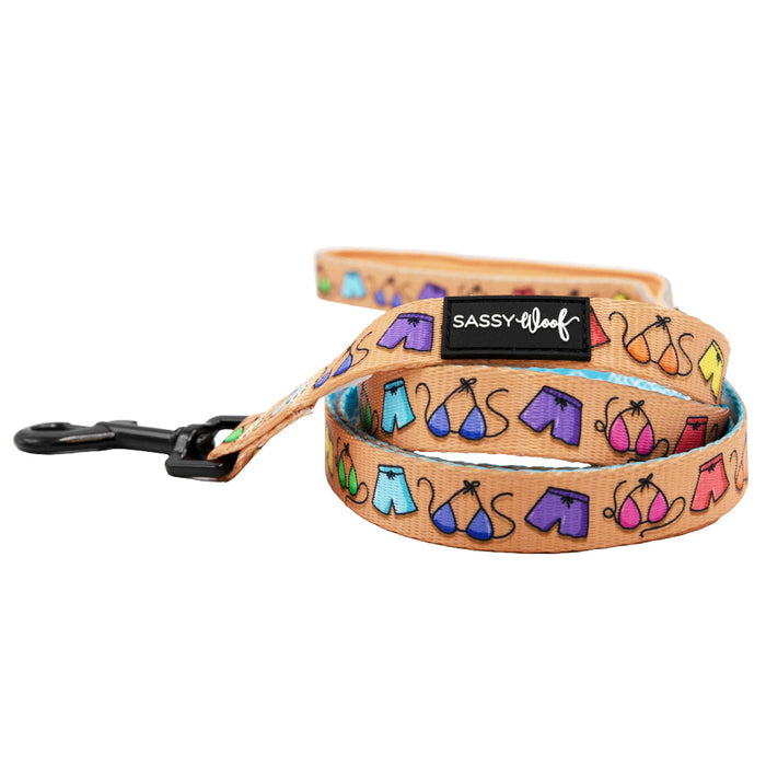 A tan dog leash from the Sassy Woof Dog Two Piece Bundle - Muscle Bod, featuring colorful cartoon-style designs and a black metal clip. The SASSY WOOF label is visible, making it perfect to pair with an Adjustable Harness.
