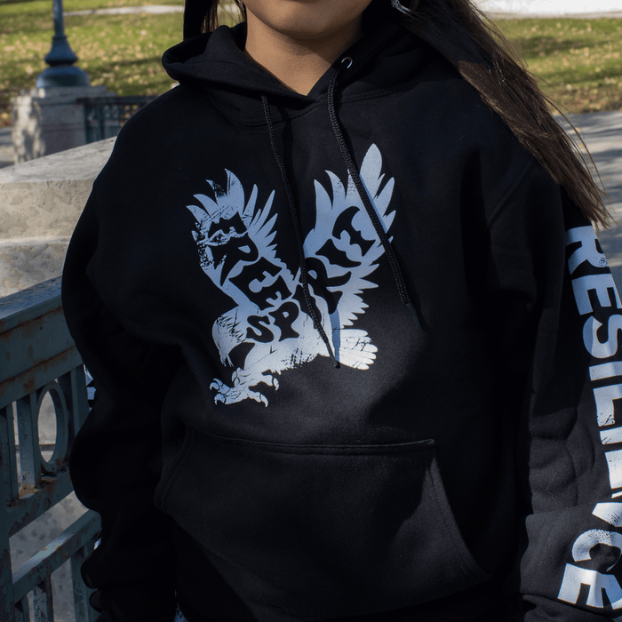Model wearing a black Free Spirit Hoodie featuring bold eagle graphics and a message of resilience.