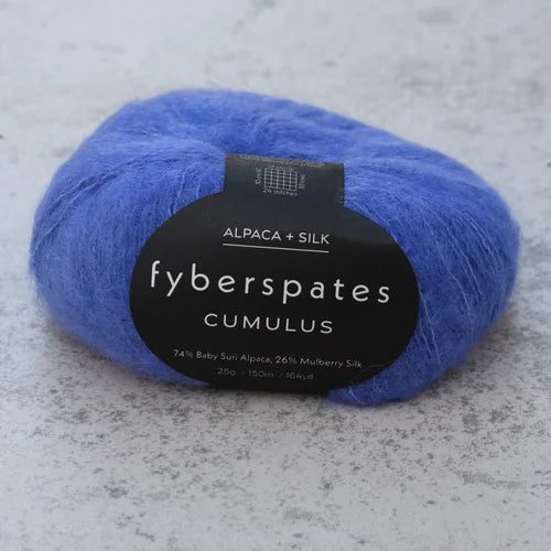 Blue yarn ball with 'fyberspates Cumulus' label on a gray surface