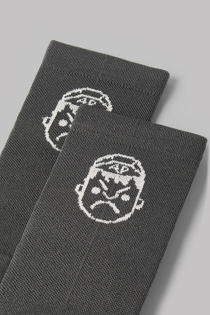 Two gray socks with white face designs on a light gray background