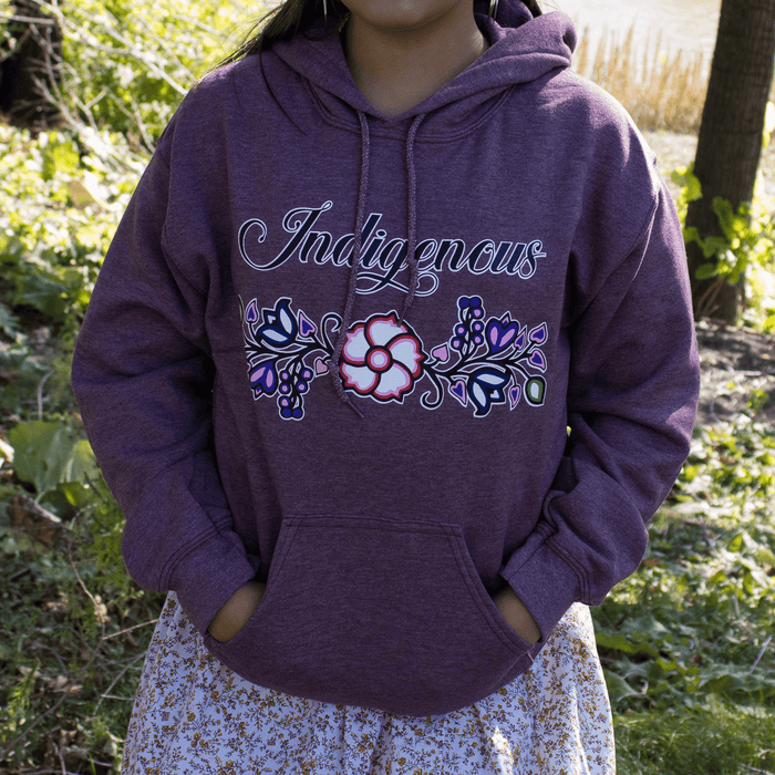 Indigenous Floral Hoodie displayed on model outdoors, showcasing vibrant floral patterns and stylish design.