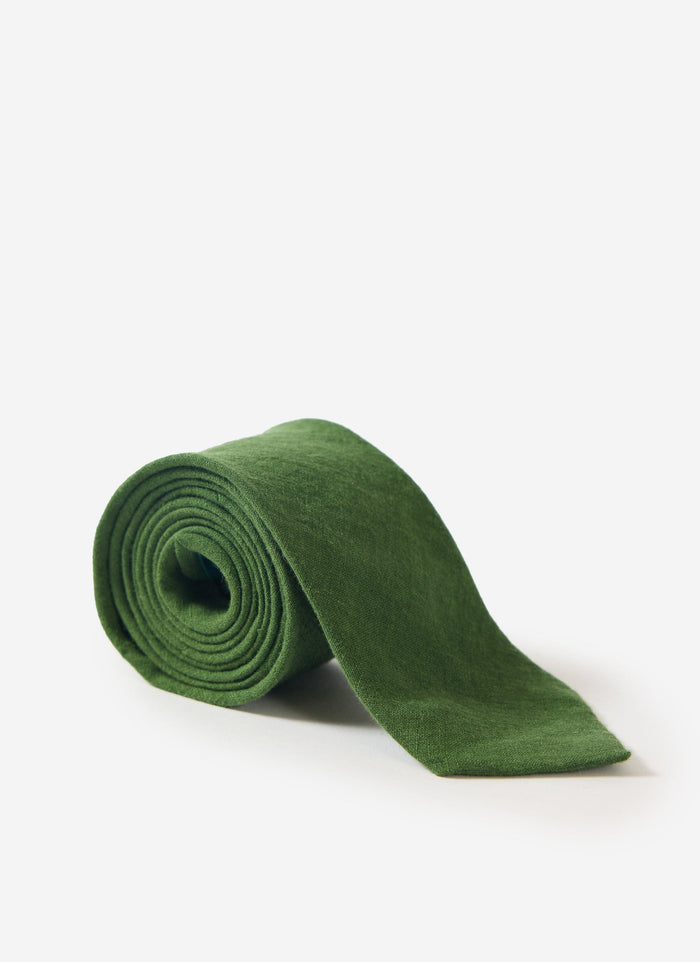 The Percival Linen Tie in forest green, neatly rolled and photographed against a clean white studio background.