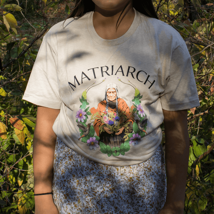 Matriarch Tee featuring an empowering graphic celebrating indigenous matriarchs amidst natural surroundings.