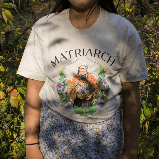 Matriarch Tee featuring an empowering graphic celebrating indigenous matriarchs amidst natural surroundings.