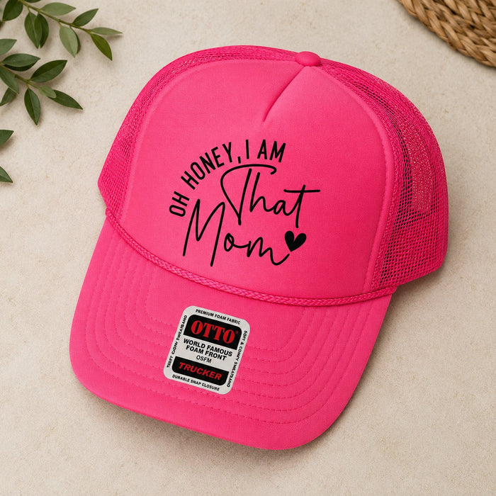Tea Shirt Shoppe Wholesale bright pink trucker hat with "Oh Honey, I am That Mom" graphic and mesh back.