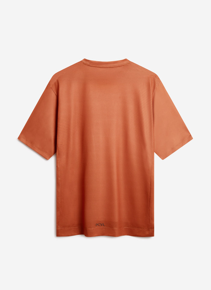 The back of the Percival PCVL Performance Top in rust, showing the ventilated mesh fabric and logo on the hem.