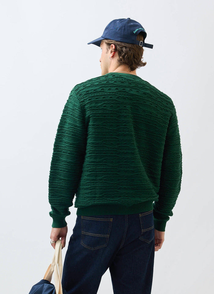 A model seen from behind wearing the Percival Tales Knitted Jumper in forest green, highlighting the unique textural knit.