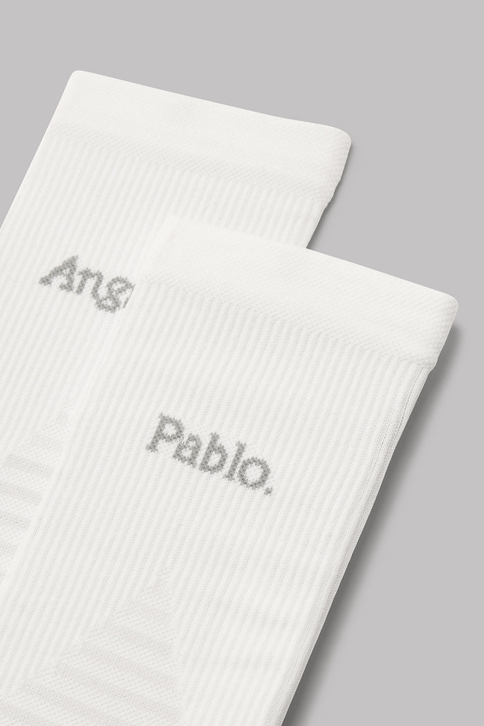 Two white socks with embroidered names on a gray background