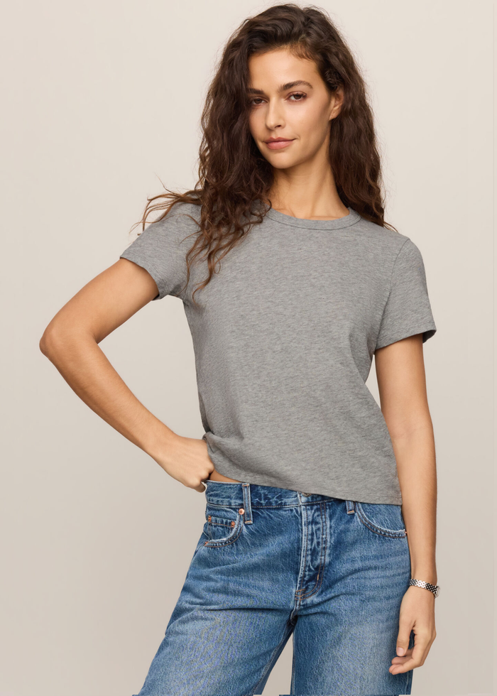 Woman wearing grey tee with her hand on her hip.