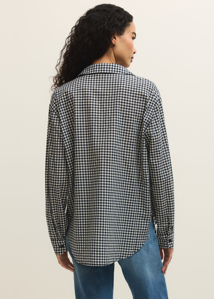 Woman turned around wearing a navy and white gingham button down with jeans